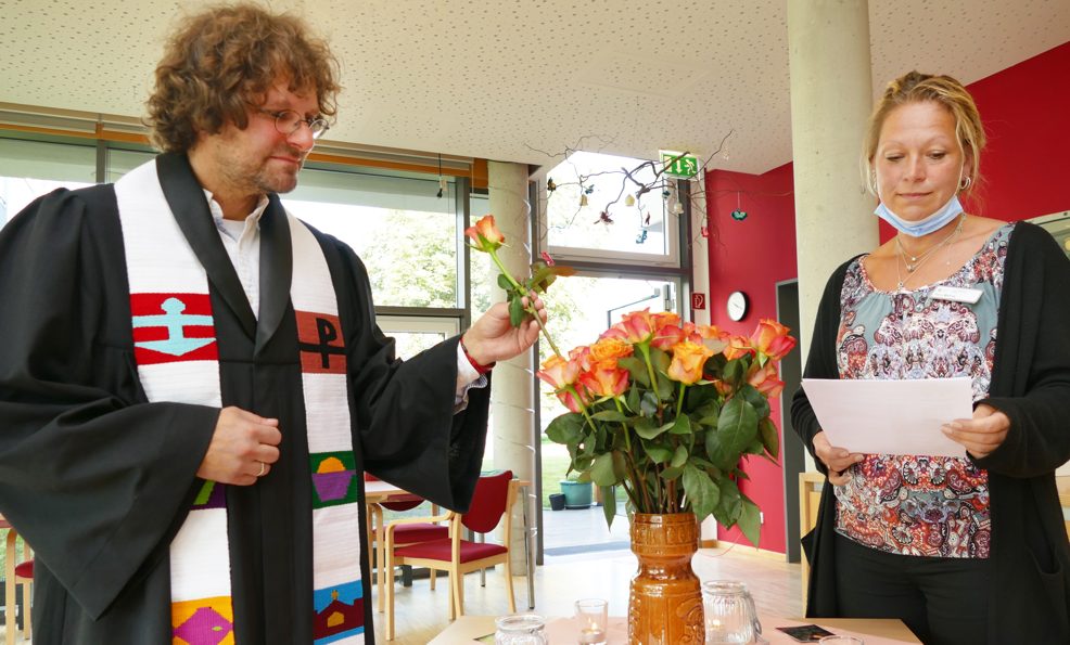Geistlicher Leiter und Heimleiterin mit Rosen bei Gedenk-Gottesdienst für Verstorbene