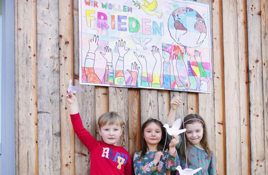 Kinder mit Friedenstauben vor Plakat für Ukraine-Hilfe