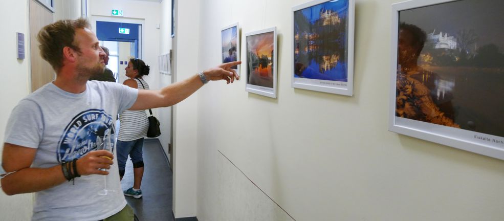 Fotograf zeigt auf eins seiner Bilder bei Ausstellungseröffnung