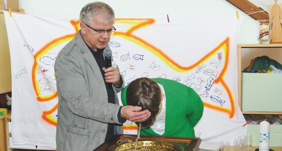 Pfarrer tauft Jugendlichen am Taufstein