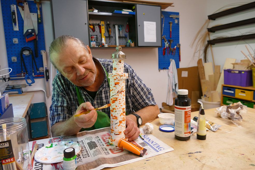 Mann malt selbst gebastelten Leuchtturm an