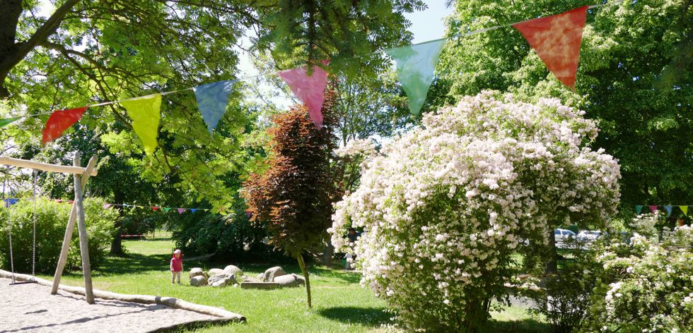 Garten Kita Nerchau mit blühenden Büschen und Wimpeln