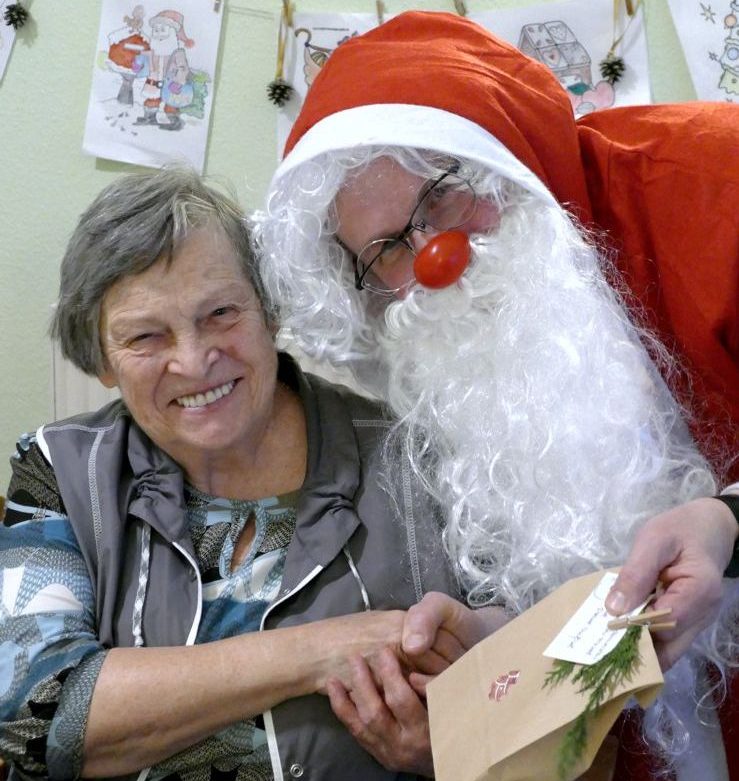 Weihnachtsmann überreicht älterer Dame ein Geschenk