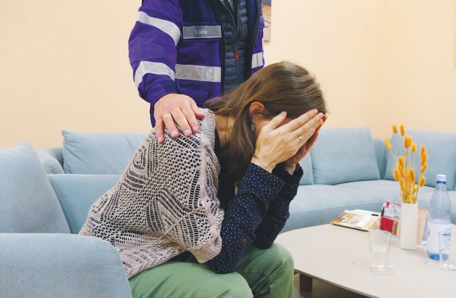 Notfallseelsorger legt Frau tröstend die Hand auf die Schulter