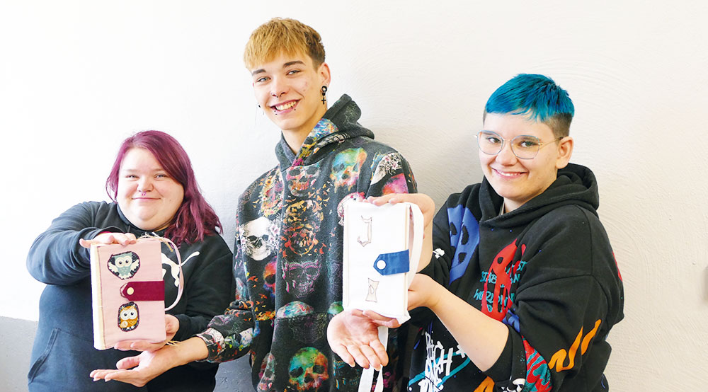 Jugendliche mit selbst genähten Buchhüllen beim Upcycling-Wettbewerb