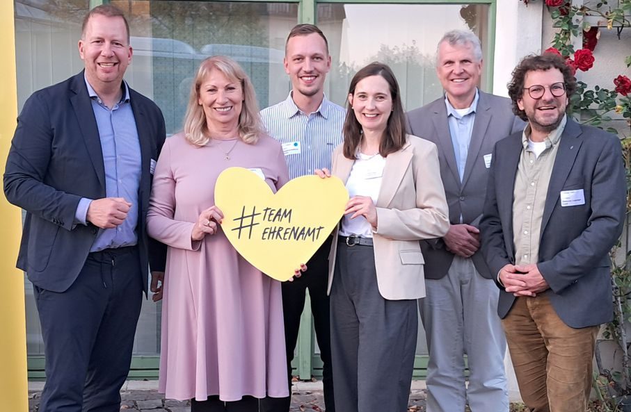Eine Gruppe mit Ministerin Köpping hält ein Papierherz mit der Aufschrift Team Ehrenamt