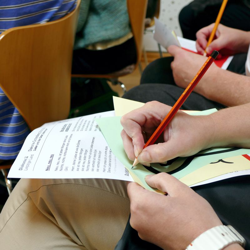 Hände, die Zettel beschreiben beim Diakonie-Gottesdienst