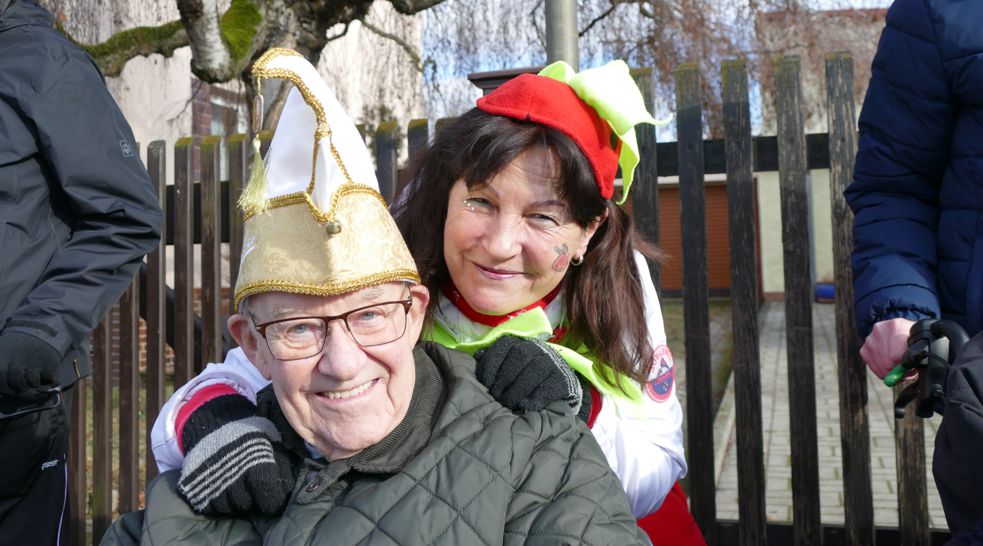 älterer Mann mit Narrenkappe und Frau mit Hut beim Warten auf den Karnevalsumzug