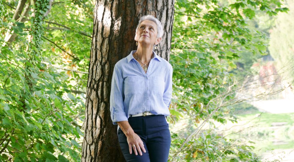 Hospizhelferin lehnt am Baum