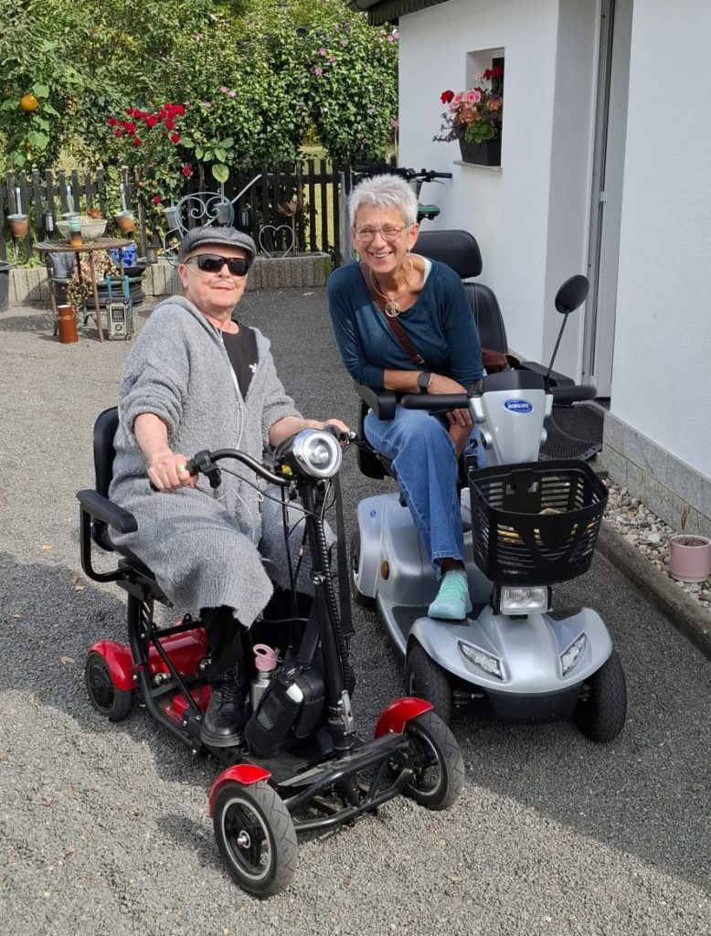 Hospizhelferin mit Klientin und Elektromobil