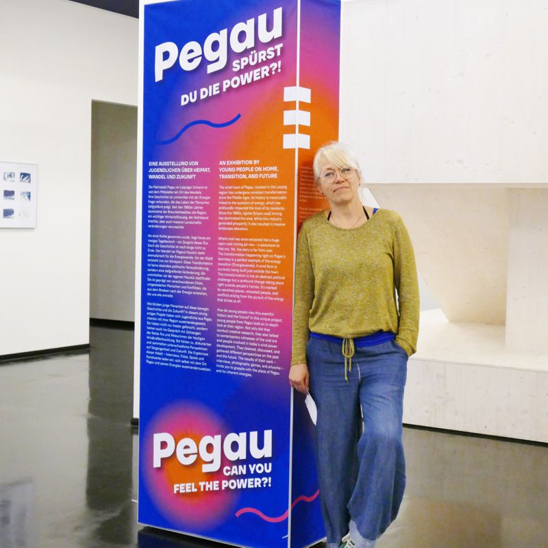 Jugendhaus-Mitarbeiter lehnt an einer Info-Säule zur Ausstellung