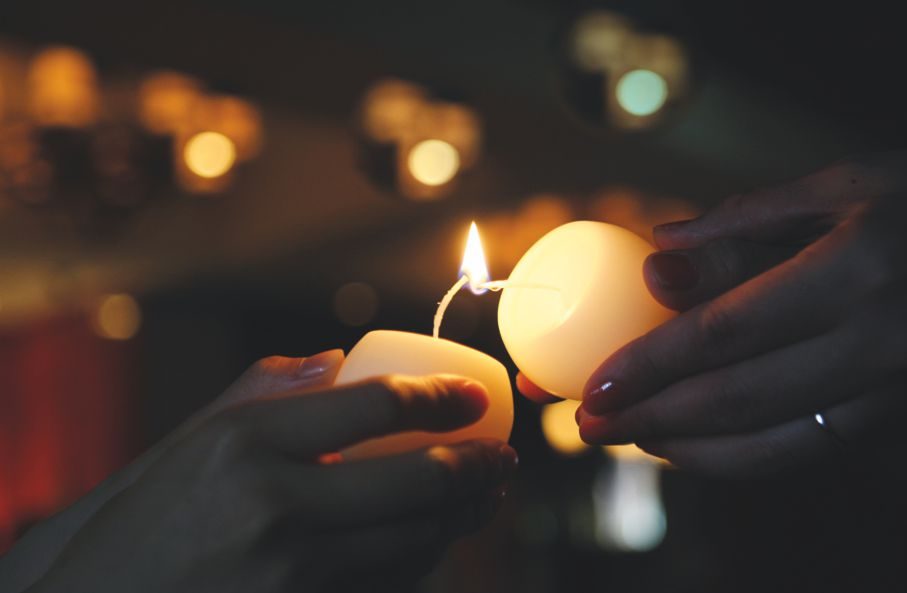 eine Kerze wird an anderer angezündet