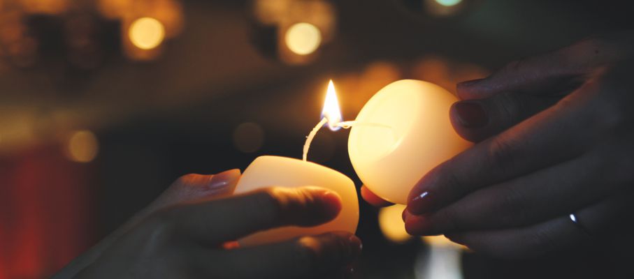 eine Kerze wird an anderer angezündet