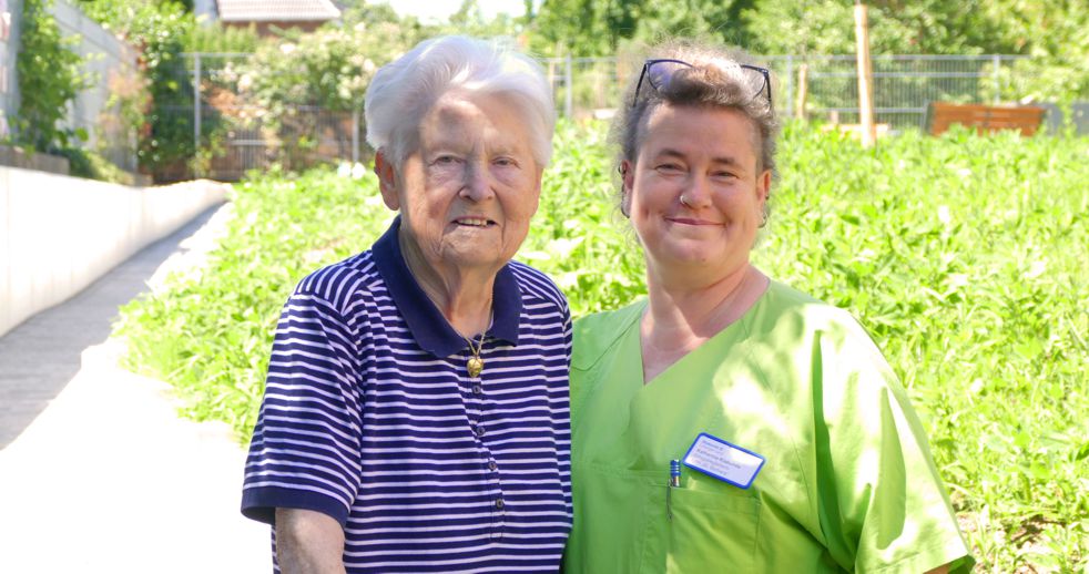 Pflegerin mit Bewohnerin im Garten