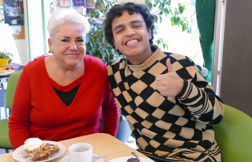 ältere Frau und jüngerer Mann an Kaffeetafel