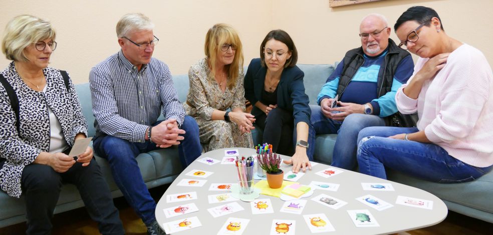 Menschen im Trauercafe sitzen um einen Tisch mit Karten