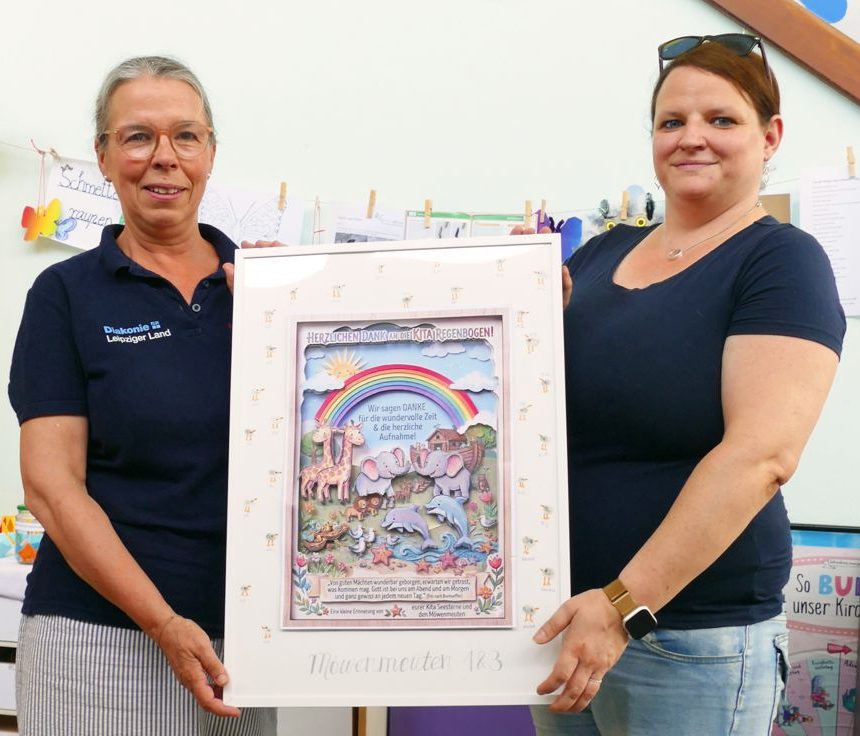 Zwei Erzieherinnen mit gebasteltem Bild, das einen Regenbogen und die Arche Noah zeigt.