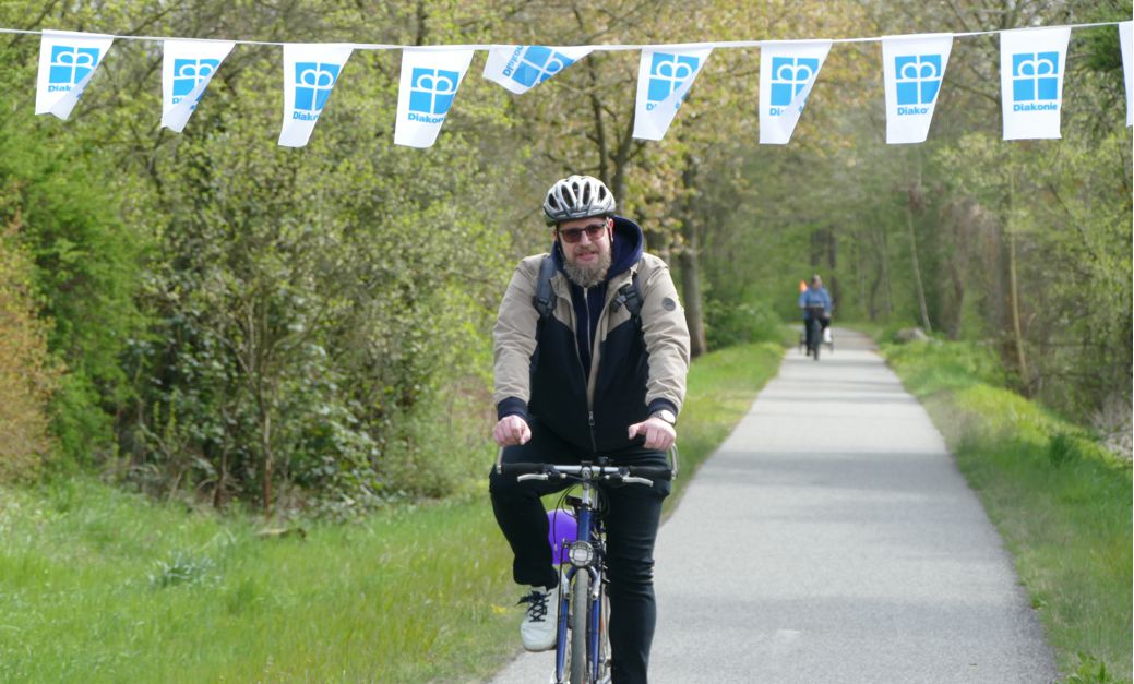 Radfahrer unter Diakonie-Wimpelkette